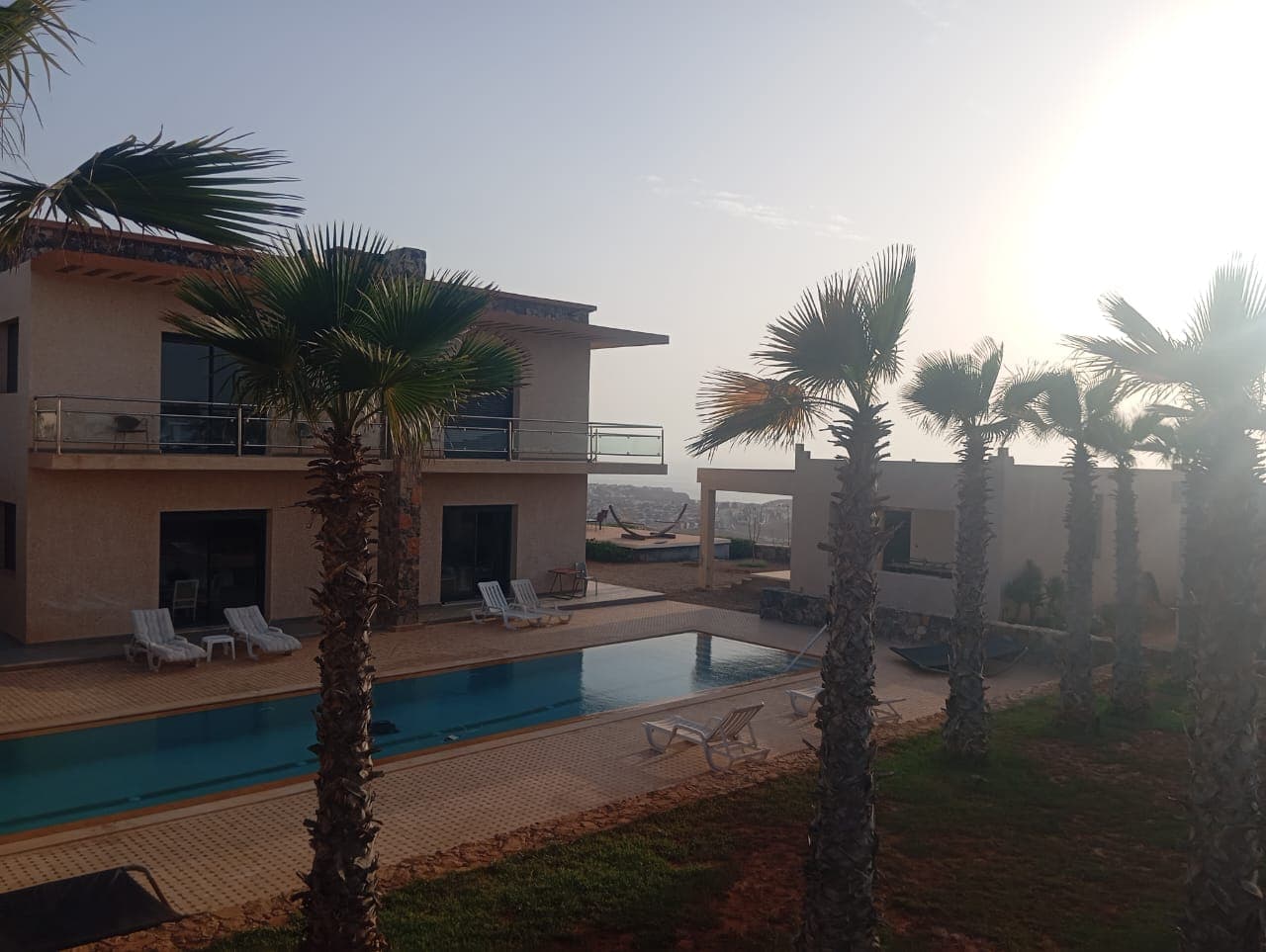 Hotel exterior with pool and palm trees during golden hour